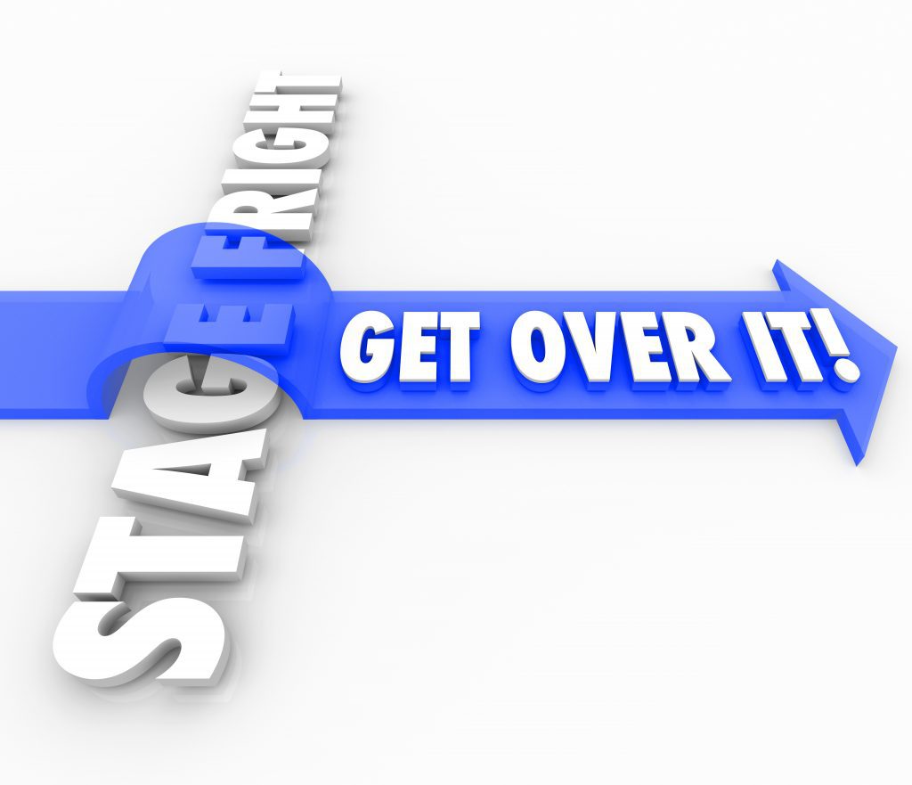 Get Over It words on a blue 3d arrow jumping over the words Stage Fright to illustrate conquering or overcoming a fear of public speaking